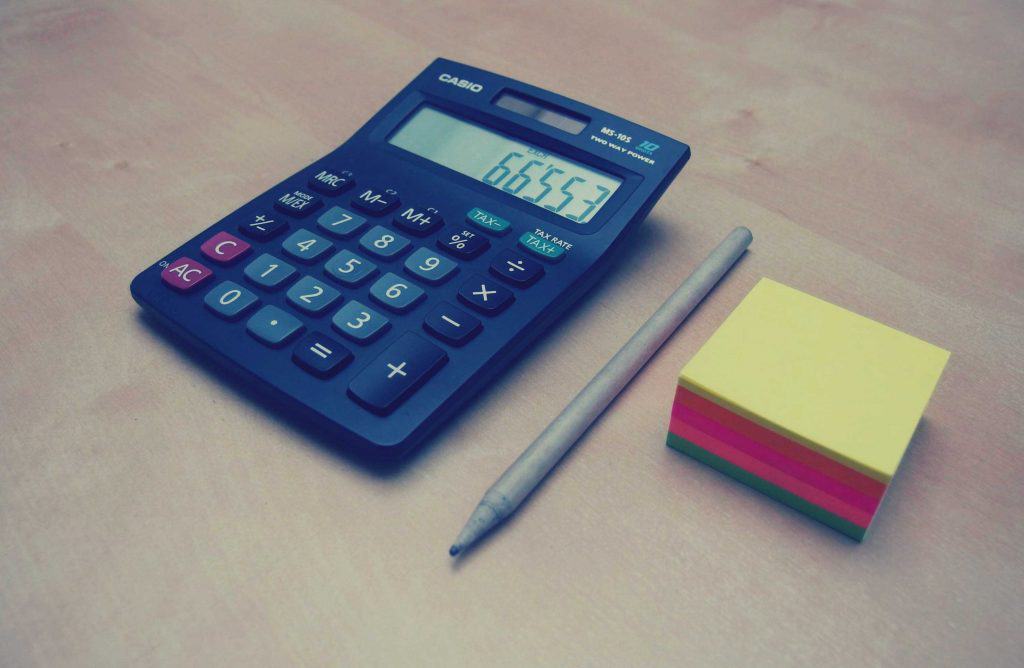 A sticky notes, pen and a calculator placed side by side